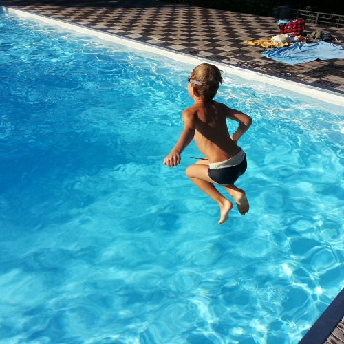 Child doing a cannon ball into a pool