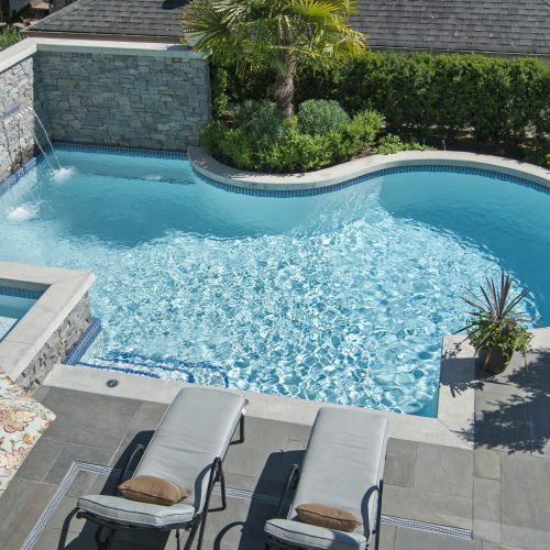 small freeform pool with built in water feature wall