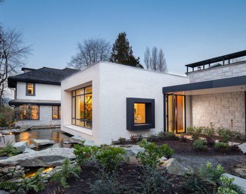 Faux rock strategically placed throughout the landscape and koi pond complement the stone facade of this modern home.