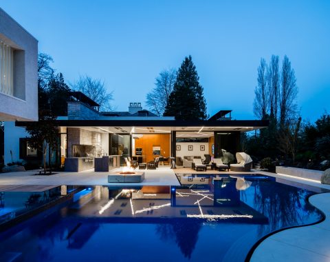 The elevated spa glows softly above the scene, while shimmering silhouettes and gentle fireside illumination create a mesmerizing interplay of light, water, and architectural form, transforming this unique aquatic retreat into a luxurious nighttime sanctuary.