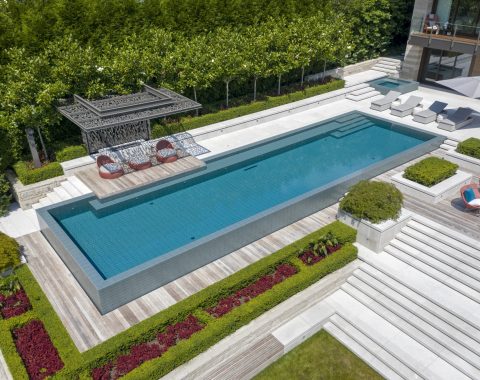 View of the long swimming pool with wooden overhang lounging area