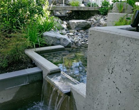 Reflecting pool running into a water feature with pebbles at the bottom