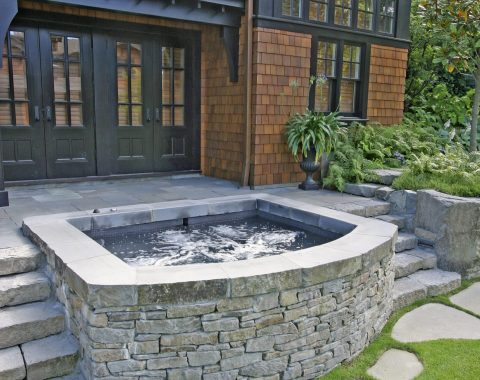 Built in hot tub and spa with water jets and natural looking exterior