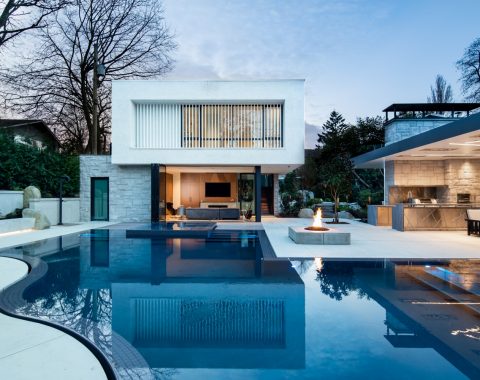 Luxury pool featuring an elevated spa, poolside fire pit, outdoor kitchen and covered lounge area.