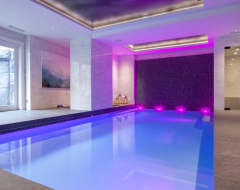 Indoor swimming pool builders have created an indoor pool experience with separate spa and color changing lights