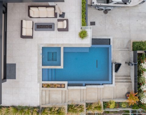 Aerial view of rectangular pool with hot tub inset finished with a galaxy blue tile; a vibrant pop of color against the muted deck tones.