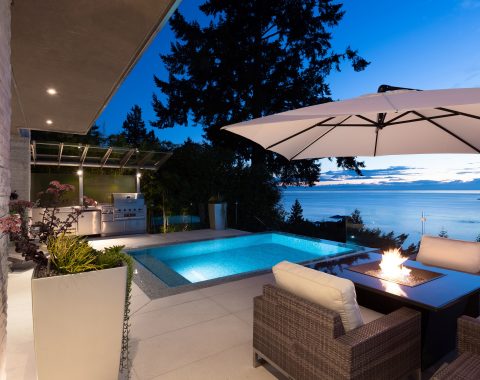 Outdoor living space at dusk with firepit and infinity pool.