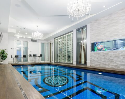 Indoor swimming pool featuring a gorgeous glass tile design and built in hot tub.