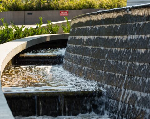 Stylish curved water feature with natural design elements to bring lush landscaping to this residential high-rise.