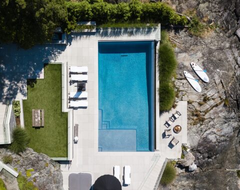 Beachfront property with a tiered backyard that features a spectacular infinity pool with vibrant blue water.