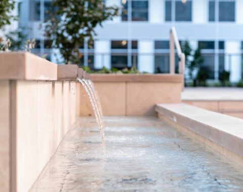 Up close side view of a set of weir spouts showing the beautiful arch of water as it gracefully hits the water below. The soothing sounds of the waterfall create a peaceful and relaxing environment.