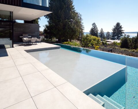 Enter a modern outdoor space with a pool side view, featuring a minimalist design with Baja shelf and neutral tones, perfect for escaping the busy life and relaxing.