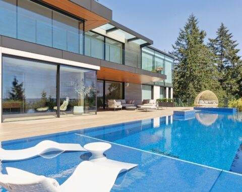 A tranquil outdoor retreat with a Zen-like ambiance, showcasing a pristine swimspace with crystal-clear water, lush greenery, and an inviting relaxing area with loungers and shade, perfect to relax at the end of your day.