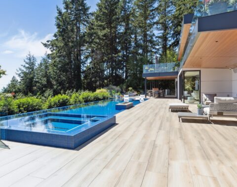 Side view of a custom outdoor swimspace featuring a deck area with a water view